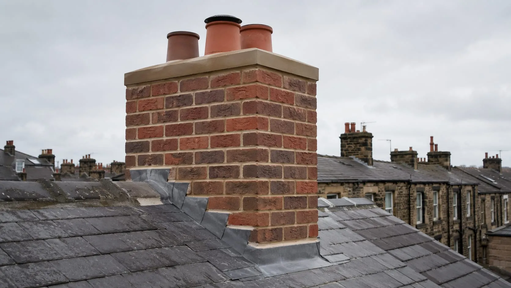 A rebuilt brick chimney stack with neat new mortar joints and clean lead flashing at the base.